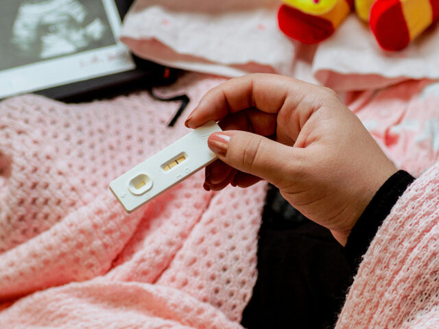 Woman holding a pregnancy tester in her hand.